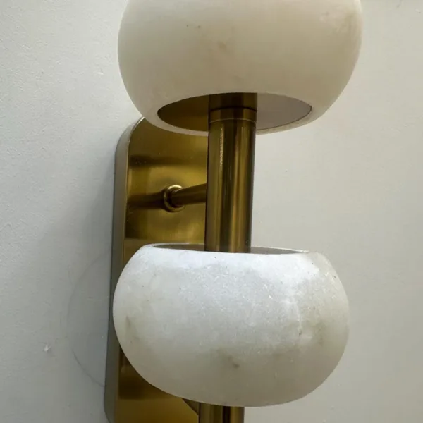 Unlit alabaster beads and rounded brass-finish wall plate up close