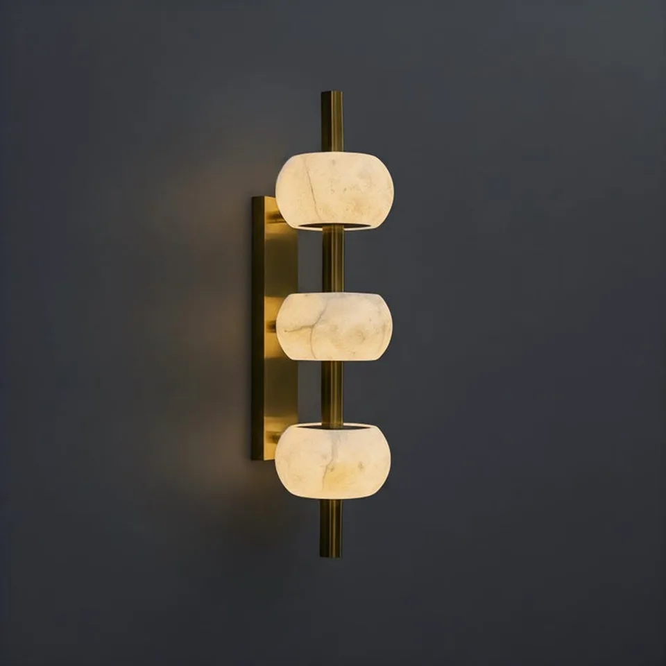 Alabaster bead wall light with three glowing stones on a brass-finish rod, grey wall