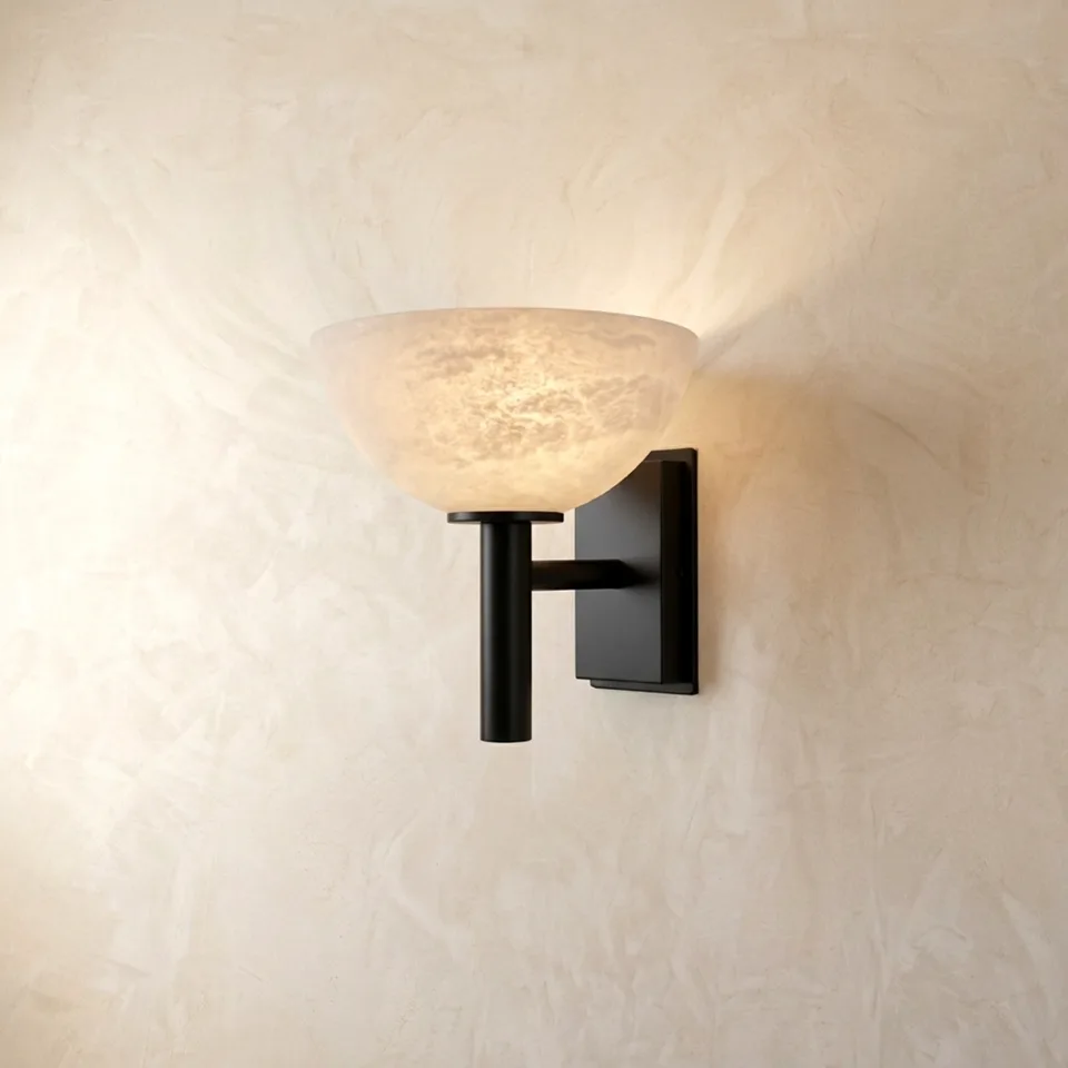 Alabaster bowl wall light on a black stem, glowing warm up a plaster wall