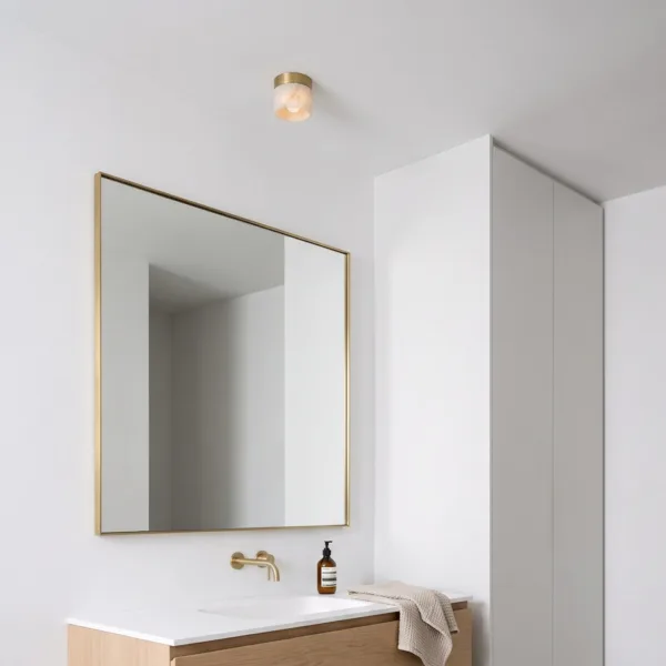 Small alabaster ceiling light in a powder room with a brass mirror