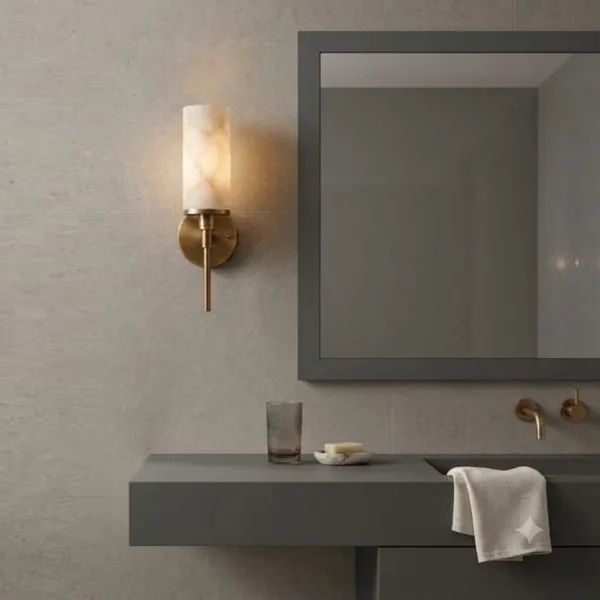 Alabaster cylinder wall lamp beside a bathroom mirror above a grey vanity