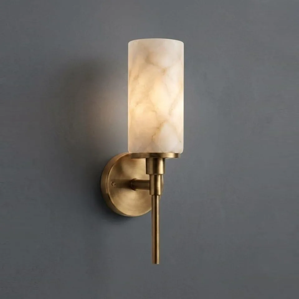 Home 3 Alabaster wall lamp glowing warm on a grey wall, brass-finish torch stem