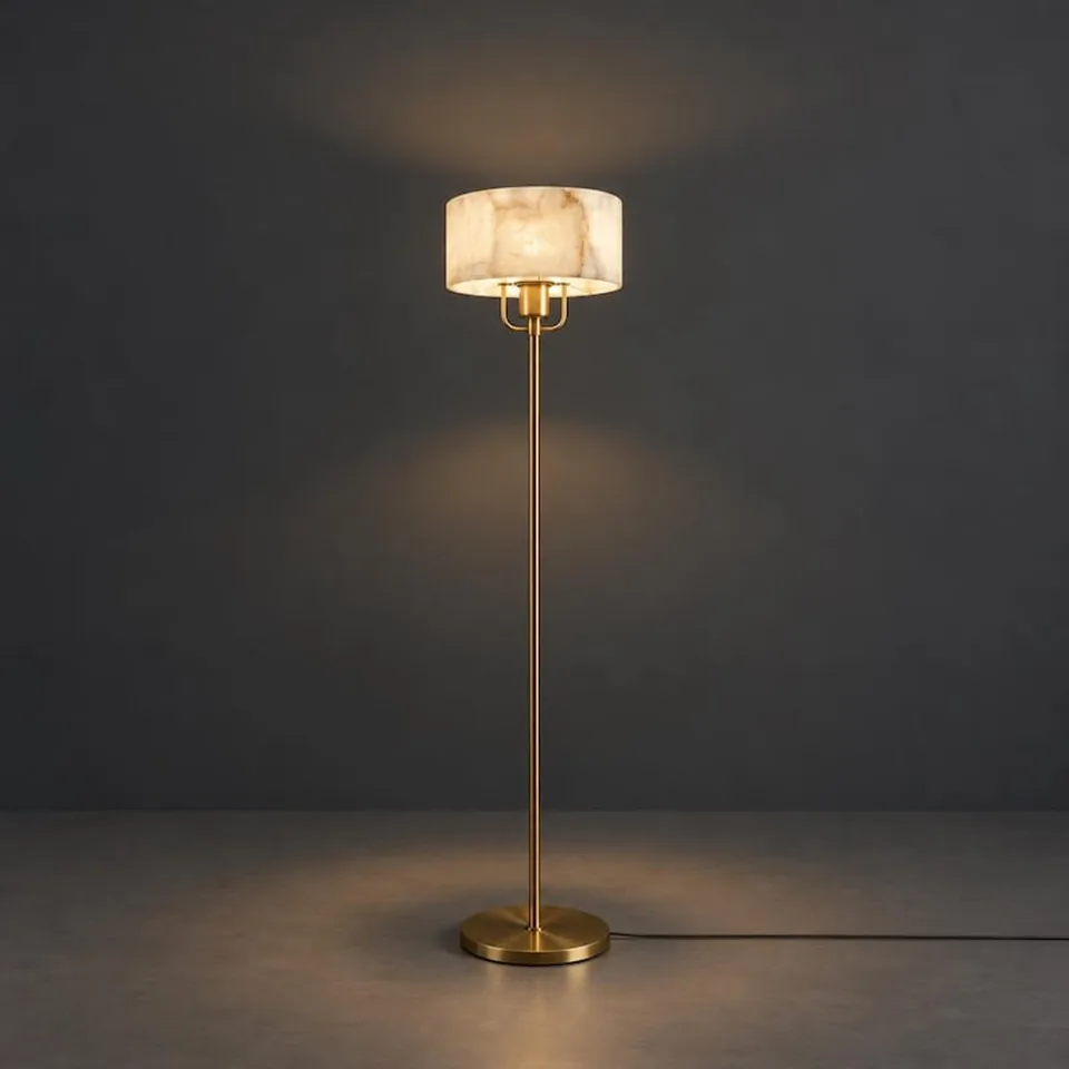 Alabaster drum floor lamp glowing warm on a slim brass-finish stem, dark background