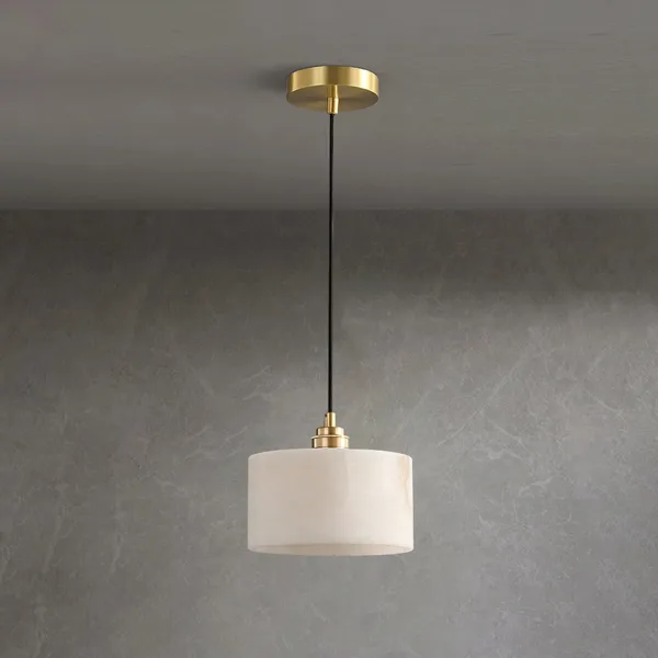 Alabaster drum pendant light with a brass ceiling canopy and black cord against a grey wall