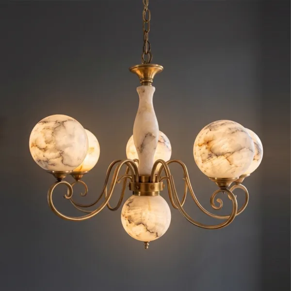 Alabaster globe chandelier glowing warm with brass scroll arms against a grey wall