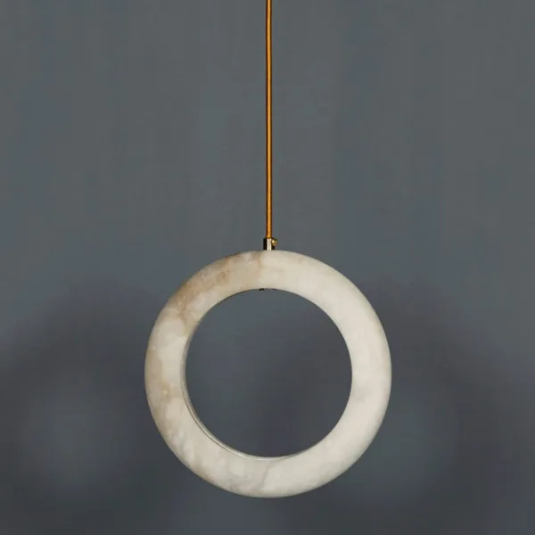 Natural alabaster halo ring pendant light hanging against a grey wall, showing the milky white veining of the stone