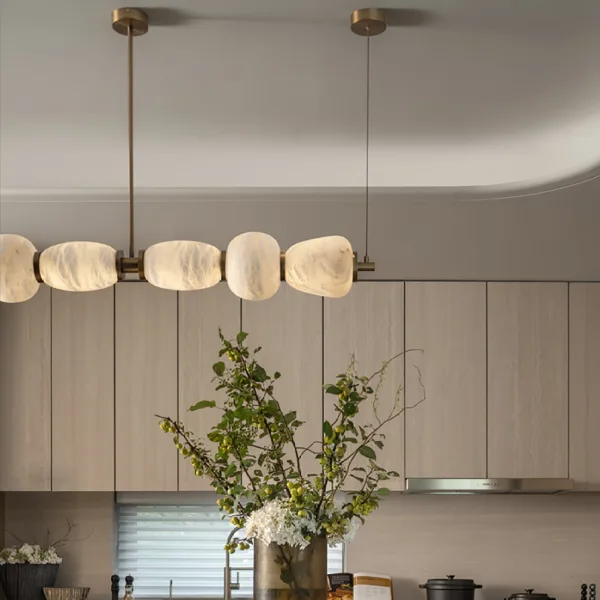 Lit alabaster shades and brass bar of the kitchen island chandelier