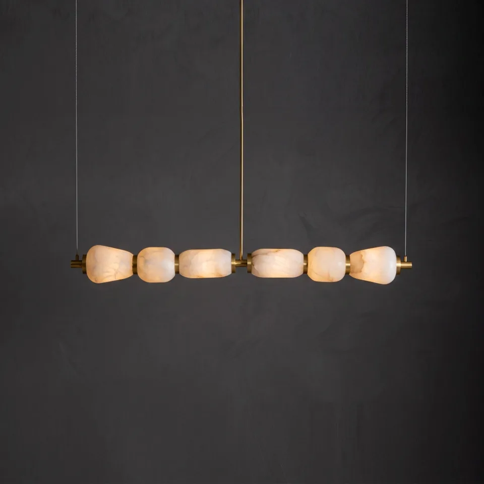 Home 2 Kitchen island chandelier with six lit alabaster shades on a brass bar, dark wall