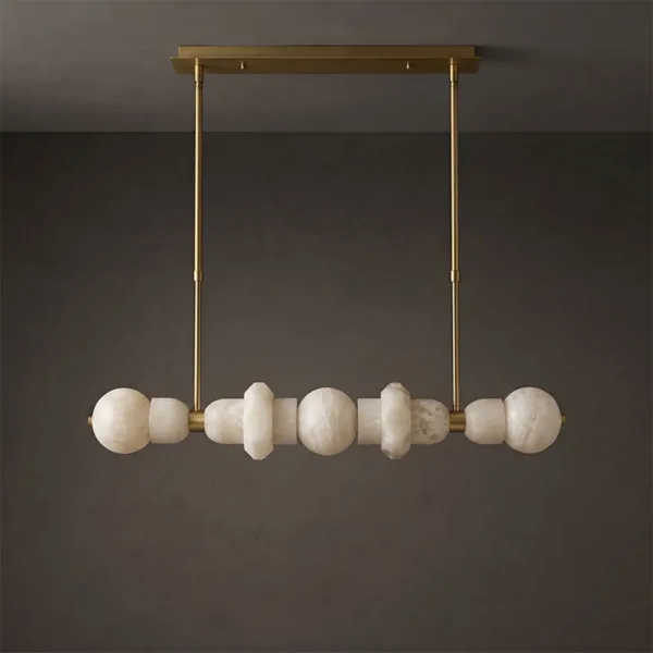 Alabaster orb linear chandelier with brass bar, unlit, against a grey wall
