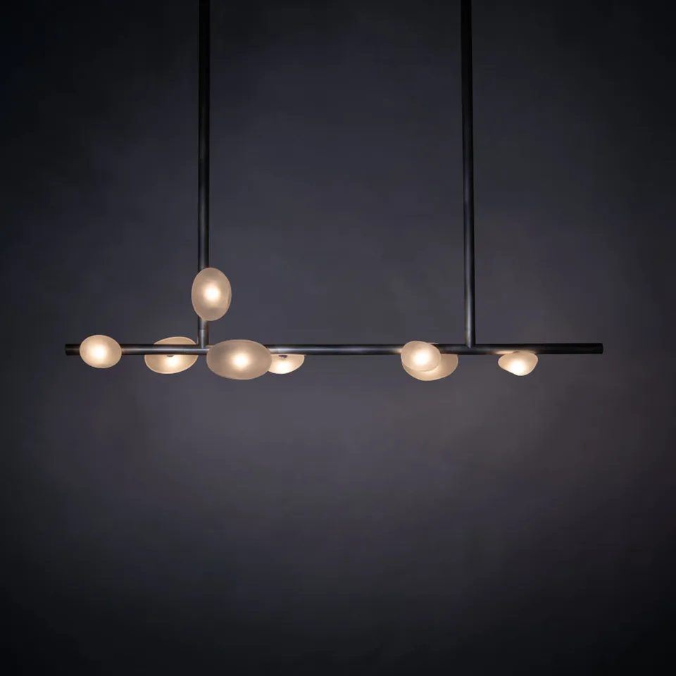 Home 3 Alabaster pebble linear chandelier with glowing pebble diffusers on a dark backdrop