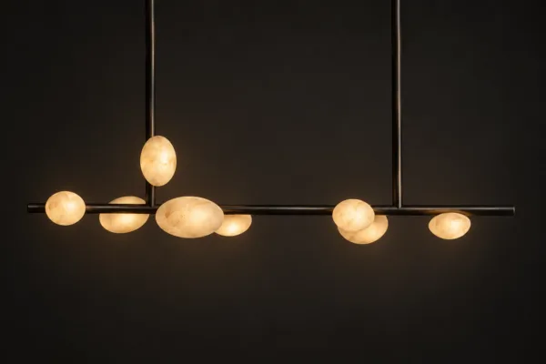 G9 alabaster pebble linear chandelier glowing warm over a dining space on a dark wall