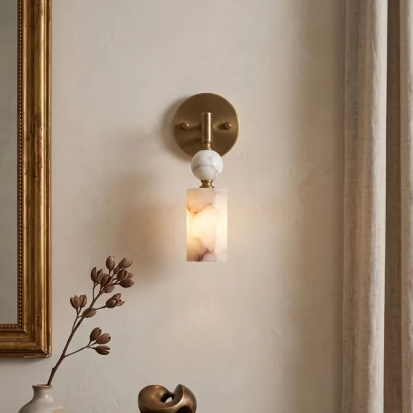 Lit alabaster pendant wall light beside a gold mirror frame