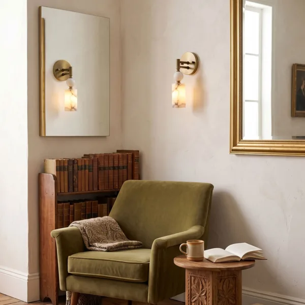 Pair of alabaster wall lights above a green armchair and bookshelf