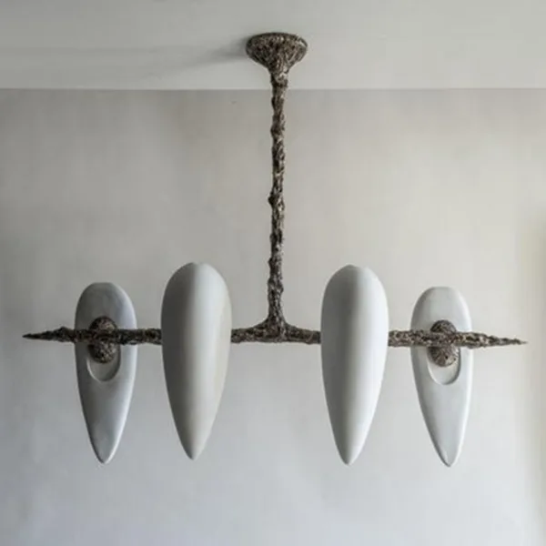 Four-alabaster teardrop chandelier unlit, seen from the front on a light grey wall