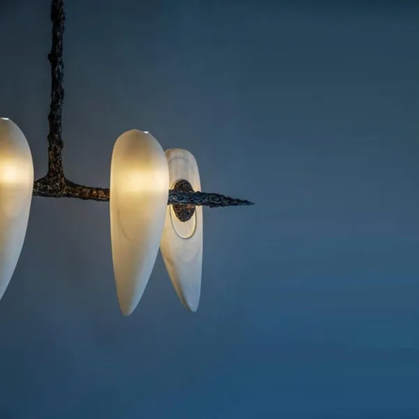 Close view of the lit alabaster teardrops on the four-alabaster chandelier against a blue wall