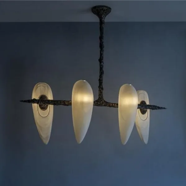 Four-alabaster teardrop chandelier lit warm against a dark blue wall