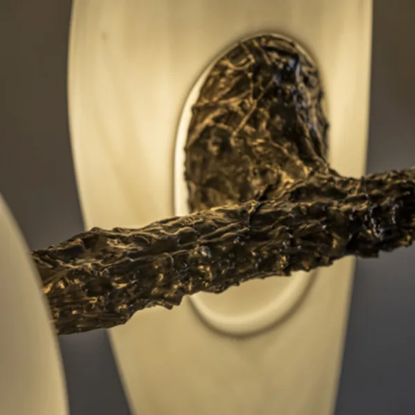 Macro close-up of the textured cast metal joint and a glowing alabaster teardrop