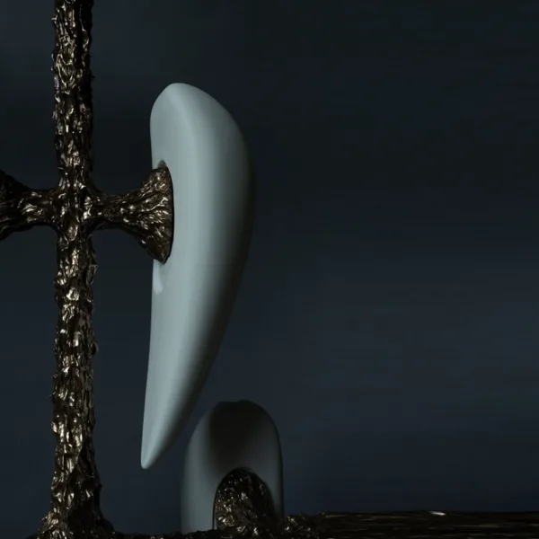 Close-up of an unlit white alabaster teardrop beside the textured cast metal frame on a dark background