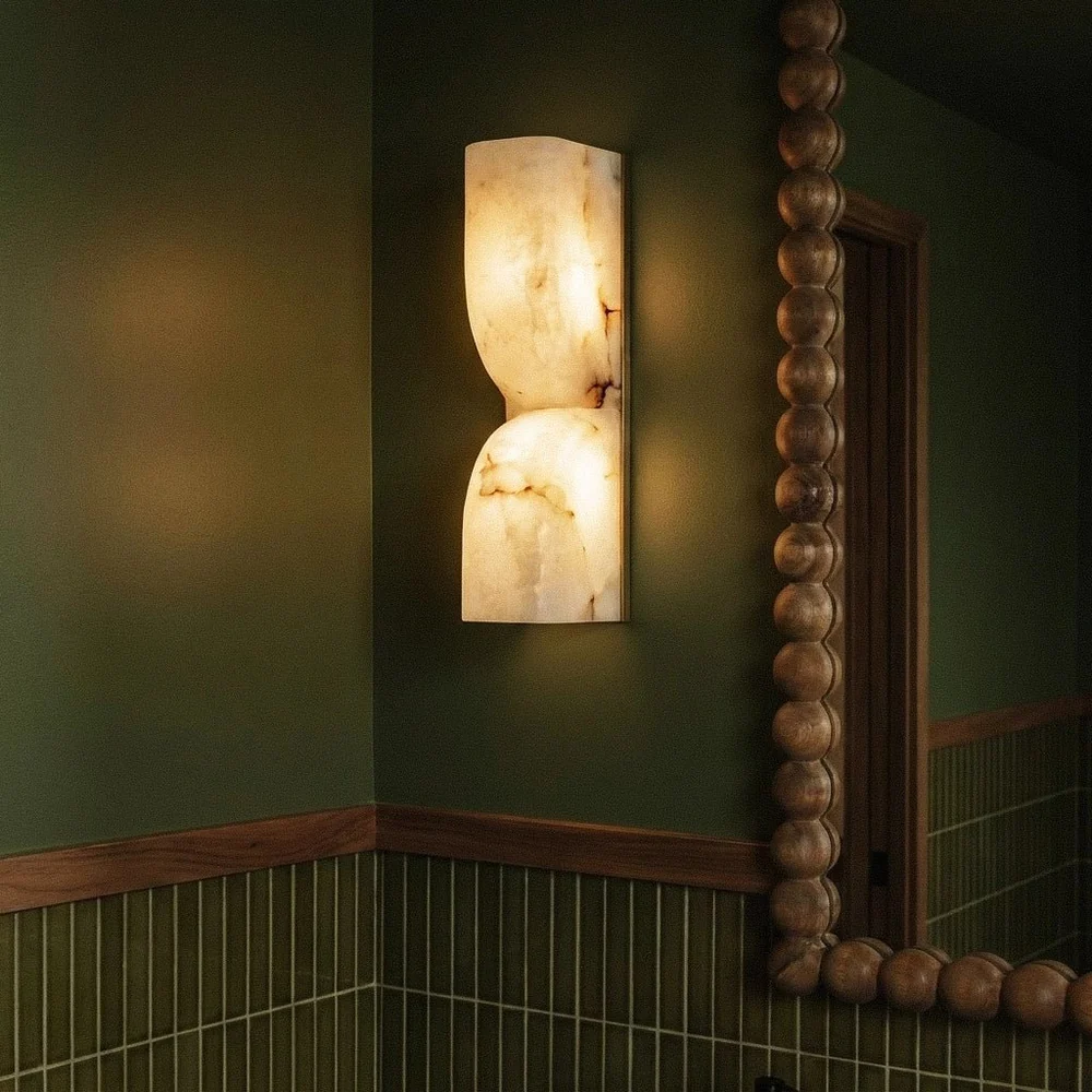 Alabaster Up and Down Wall Light – Carved Natural-Stone Sconce, 35 cm 5 Alabaster wall light glowing beside a wooden bead mirror on a green powder room wall