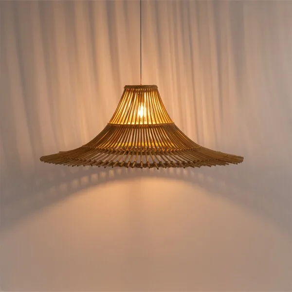 Bamboo pendant light lit warm, its 43-inch flared shade of bamboo rods casting striped shadows on a sheer curtain