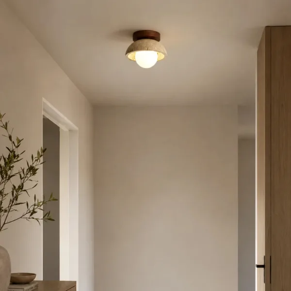 Travertine and wood ceiling light glowing above an entrance passage with an olive branch vase
