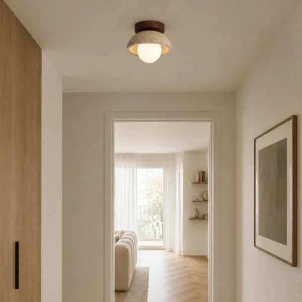 Small travertine flush mount lighting a white hallway that opens into a bright living room