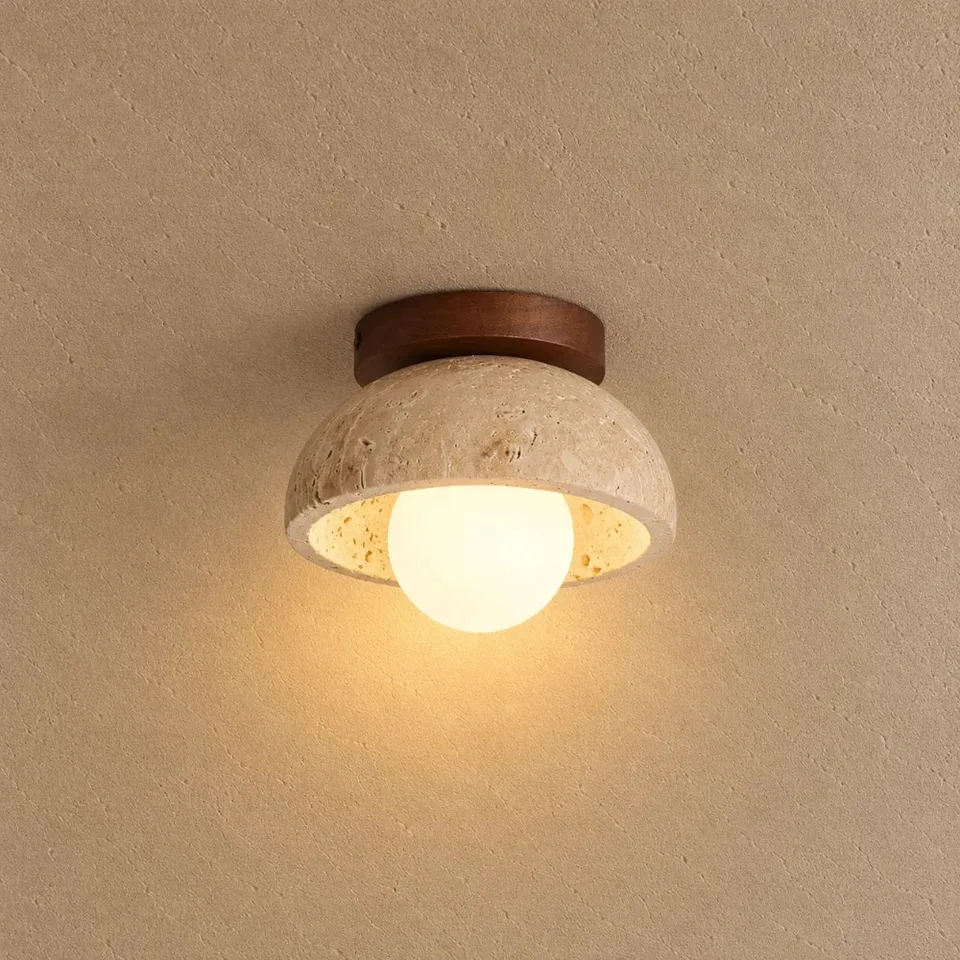 Home 3 Travertine bowl ceiling light lit warm, its opal glass globe glowing against a beige ceiling