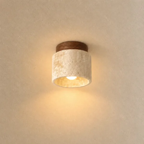 Cylindrical ceiling light in natural travertine under a walnut-tone wood canopy, lit warm on a beige ceiling