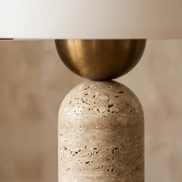 Detail of the brushed brass-finish ball between the travertine column and the glass dome