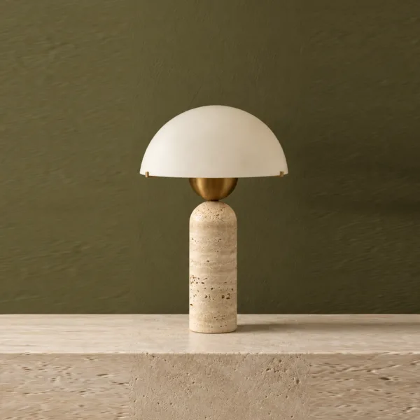 Travertine table lamp with an opal borosilicate glass dome on a stone ledge against an olive green wall