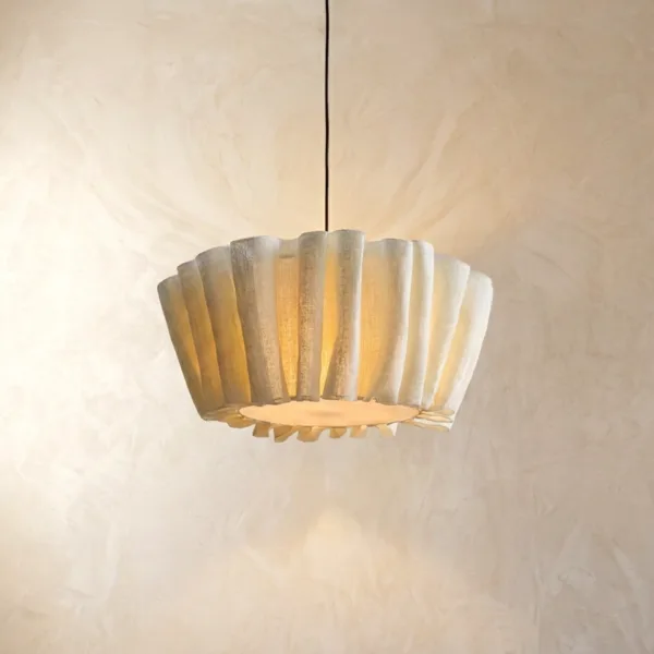 Draped fabric pendant light glowing softly with a warm light against a plaster wall