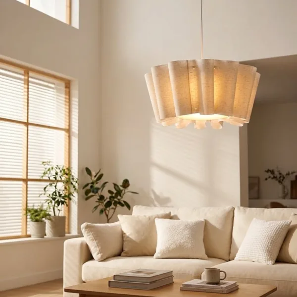 Draped fabric pendant light lit warmly above a coffee table and cream sofa in a bright living room with tall windows
