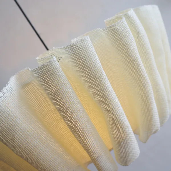 Close-up of the open-weave fabric folds on the draped fabric pendant light glowing from within