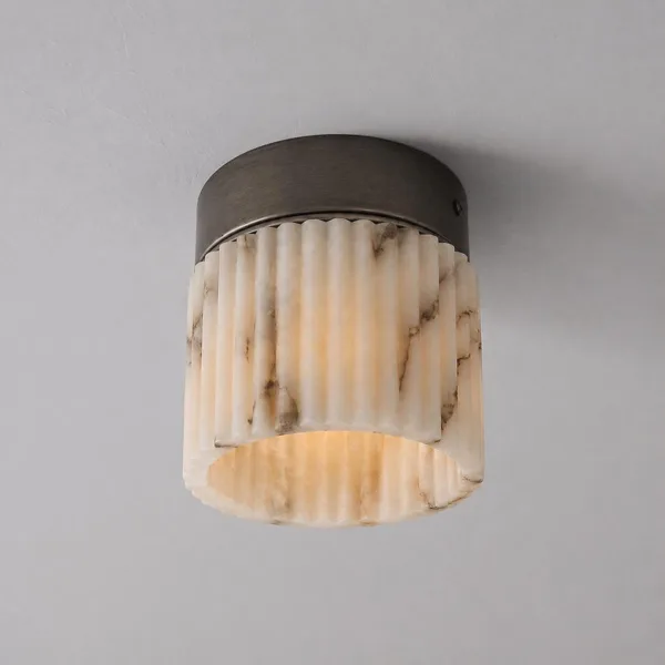Close-up of the lit fluted light, warm glow through hand-carved alabaster flutes and the open base