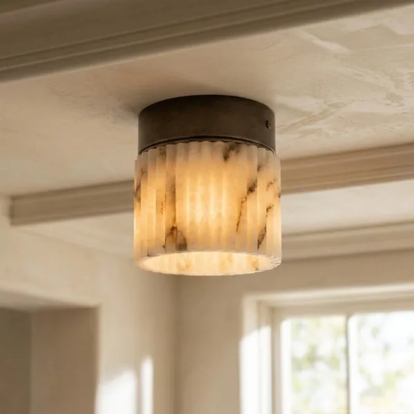 Alabaster fluted light glowing on a beamed ceiling near a sunlit window