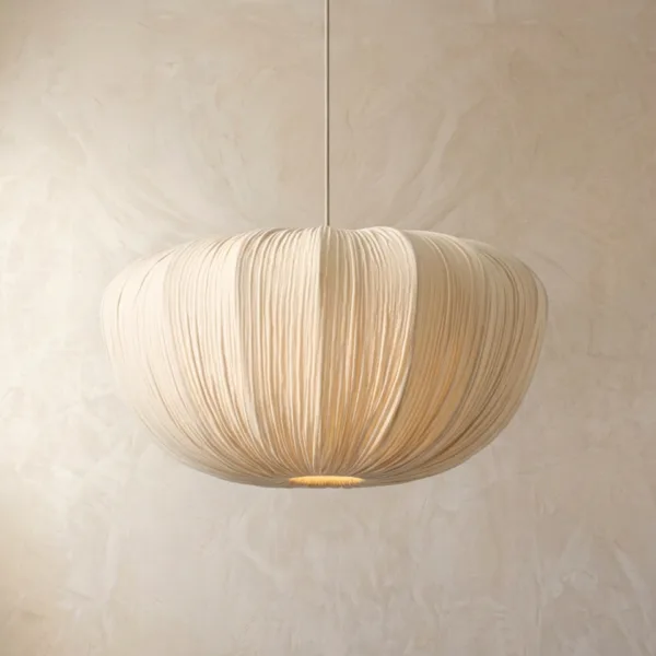Japanese fabric cloud pendant light glowing softly with a warm light at its base against a plaster wall