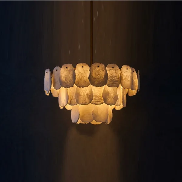 Three-tier alabaster chandelier glowing against a dark wall