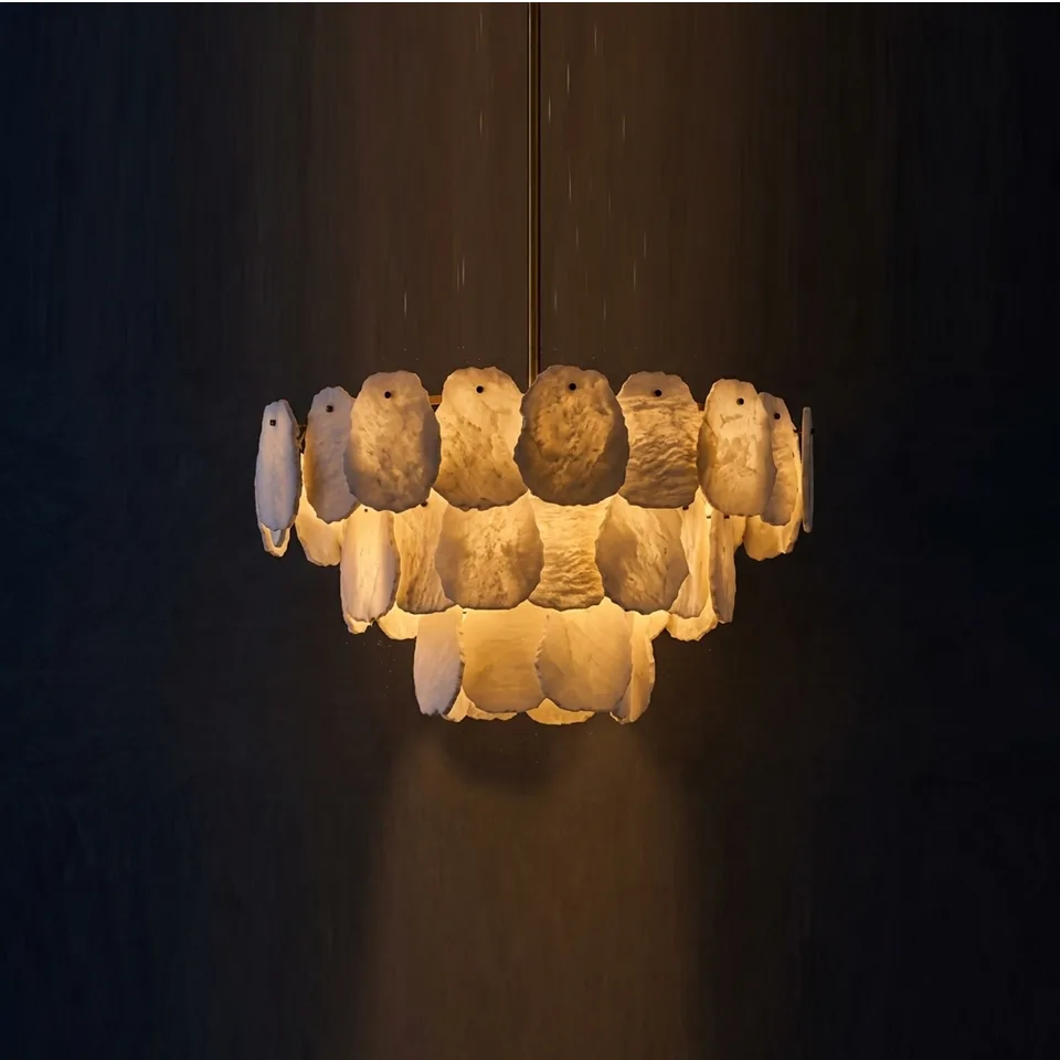Three-tier alabaster chandelier glowing against a dark wall