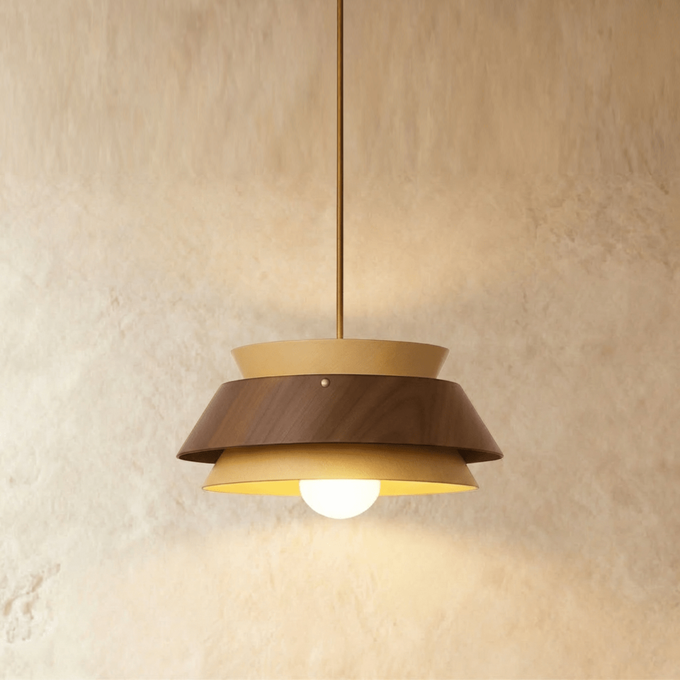Layered wood pendant light with walnut and oak tiers glowing against a plaster wall