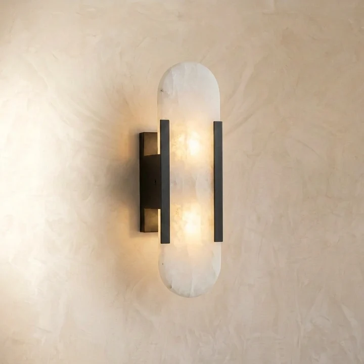 Linear alabaster wall light with a black-finish stainless steel frame, glowing warm through the natural stone on a plaster wall