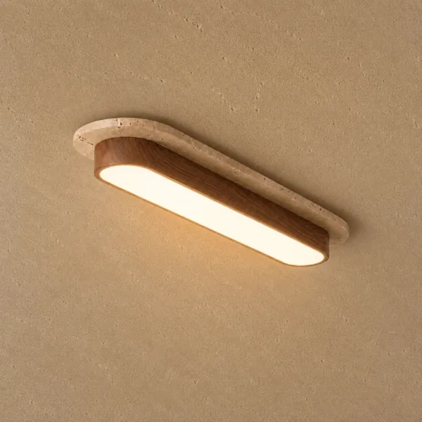 Long oval travertine ceiling light glowing warm on a textured beige ceiling
