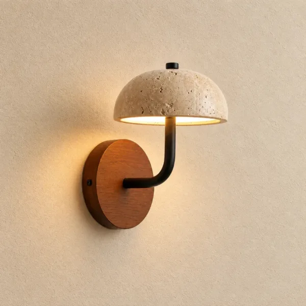 Mushroom wall light in natural travertine, lit warm on a cream wall above its round wood backplate