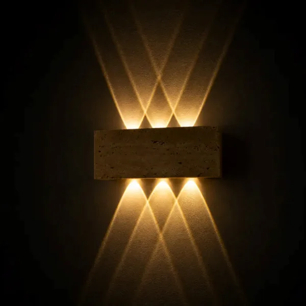 Outdoor up and down light in travertine glowing in the dark, six warm beams forming a starburst