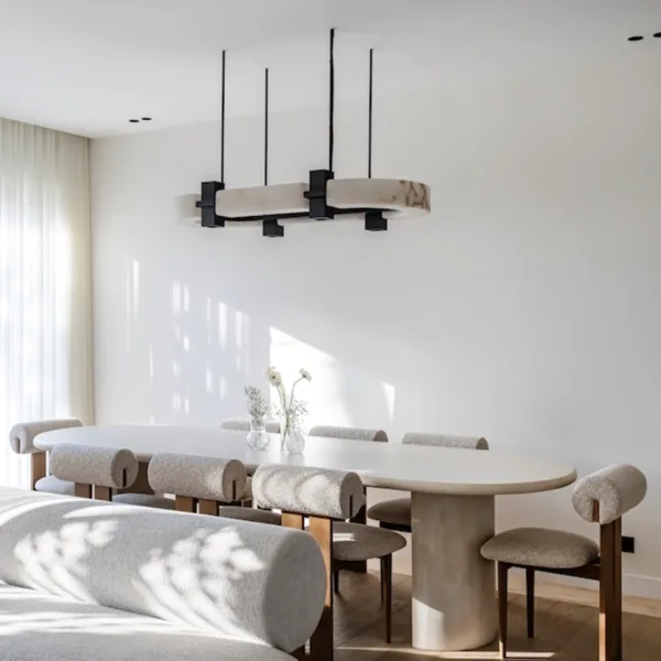 Oval chandelier above a long dining table in a bright dining room