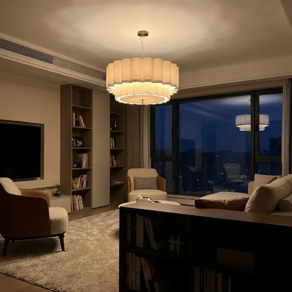 Scalloped linen drum pendant light glowing warm in an evening living room