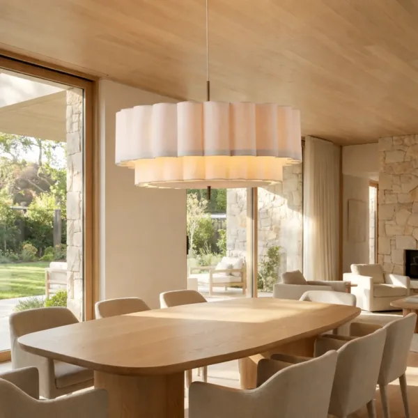 Scalloped linen drum pendant light over a long dining table in a wood-ceiling room