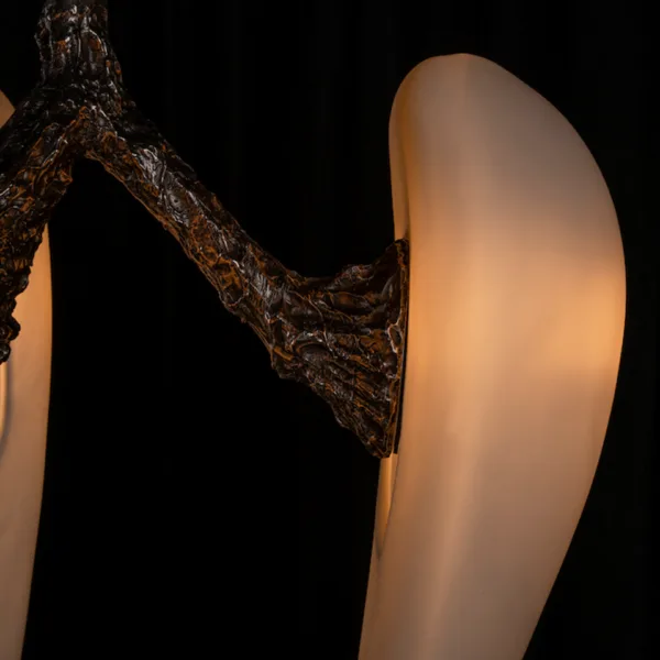 Textured metal arm holding a glowing alabaster drop, close-up