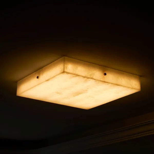 Square alabaster flush mount light glowing warm in a dark room