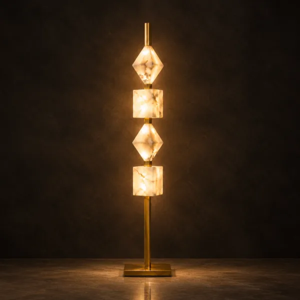 Stacked alabaster floor lamp glowing warm against a dark wall, brass-finish column