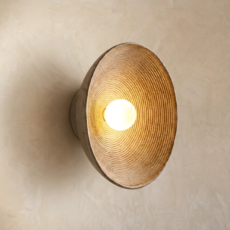 Turned teak wood bowl wall light glowing warm around a glass ball on a plaster wall
